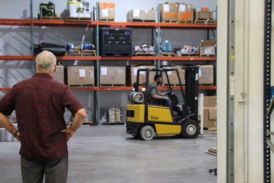 workers at a warehouse, one driving a forklift